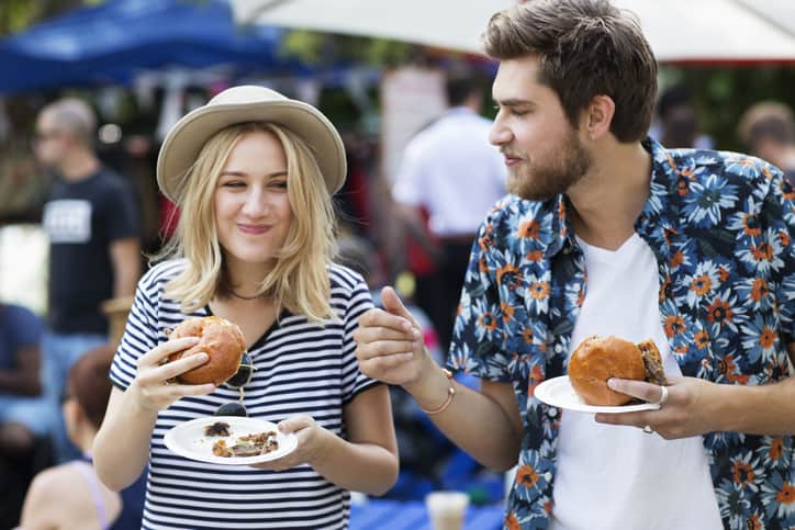 Couple eating burgers at food market