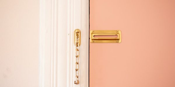An open door chain lock on a pink door.