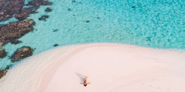 An aerial drone view of woman on a sandy beach.