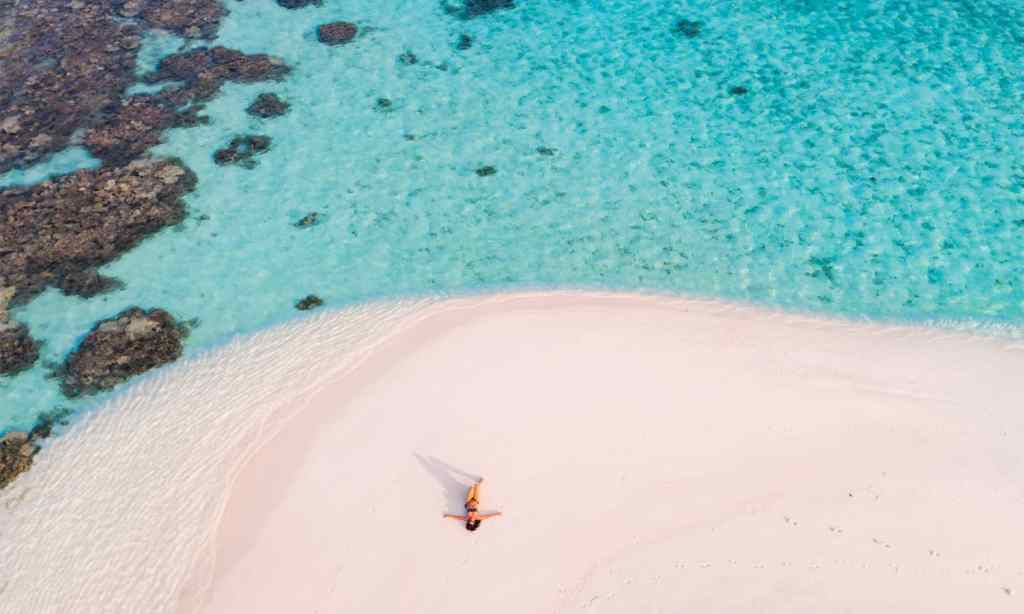 An aerial drone view of woman on a sandy beach.