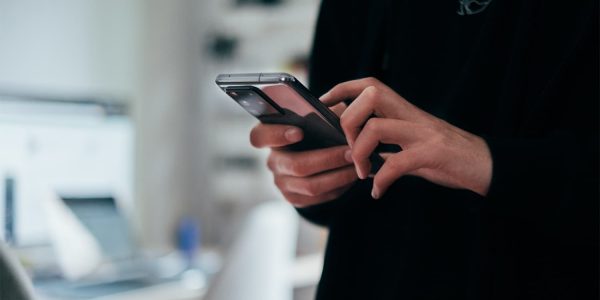 Close-up of someone in a black jumper using a phone.