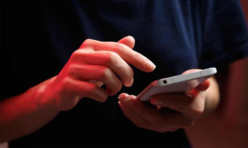 A young woman in a black shirt holding a phone.