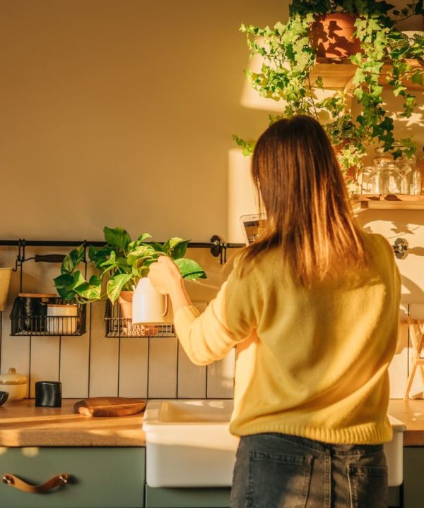 woman watering plants in kitchen