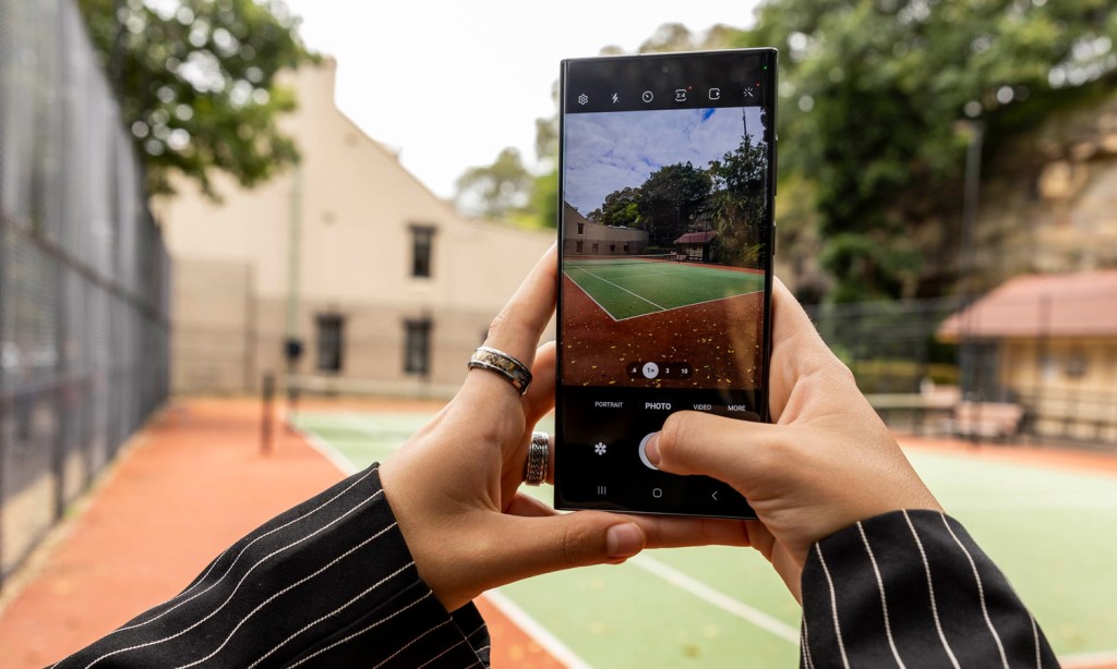 Feminine hands taking a photo of a basketball court with the Samsung Galaxy S23 Ultra.