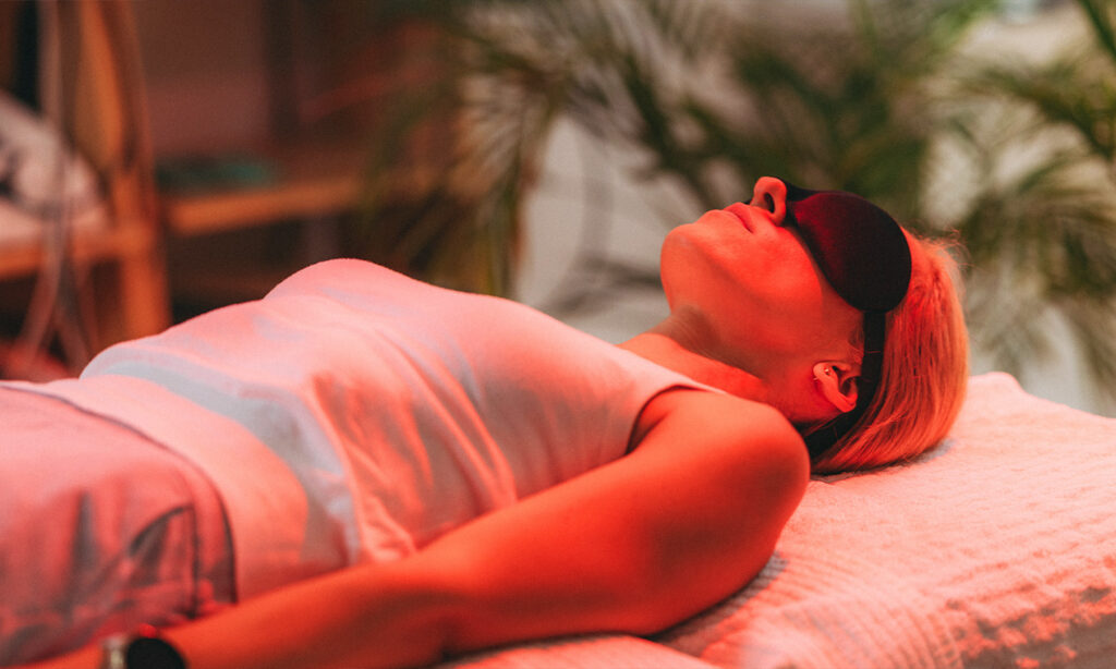 Woman undergoing psychedelic therapy laying on a table with a blindfold on.