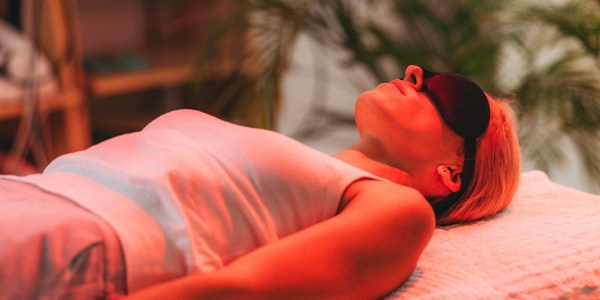 Woman undergoing psychedelic therapy laying on a table with a blindfold on.