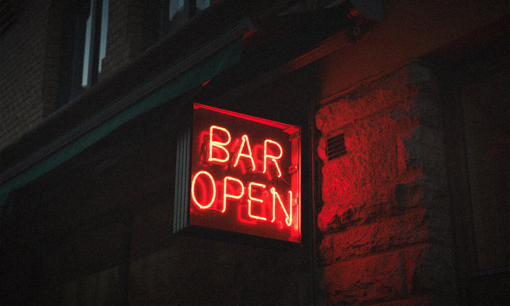 A red glowing neon sign reading 'bar open' to indicate venues and pubs that can survive without pokies.