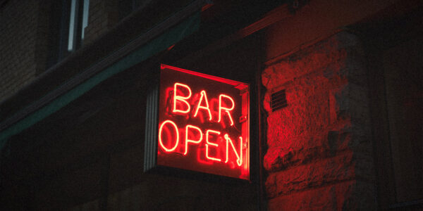 A red glowing neon sign reading 'bar open' to indicate venues and pubs that can survive without pokies.