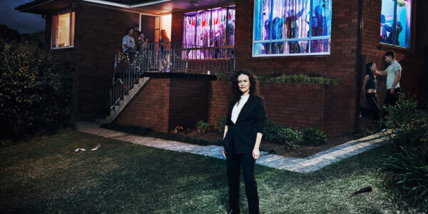 Photo showing journalist Jess Hill in front of a house party of young people to illustrate her new series 'Asking for It' on SBS.