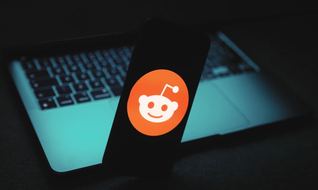 An image showing the Reddit logo against a dark laptop background to illustrate the Reddit blackout.