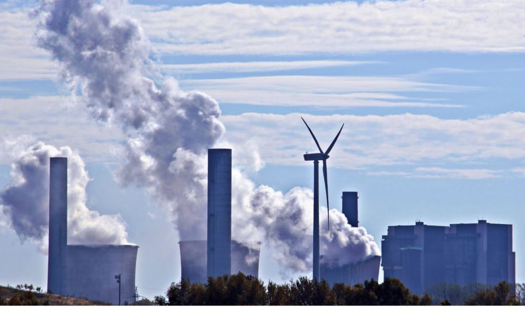 An image showing a wind generator in front of a coal fired power station