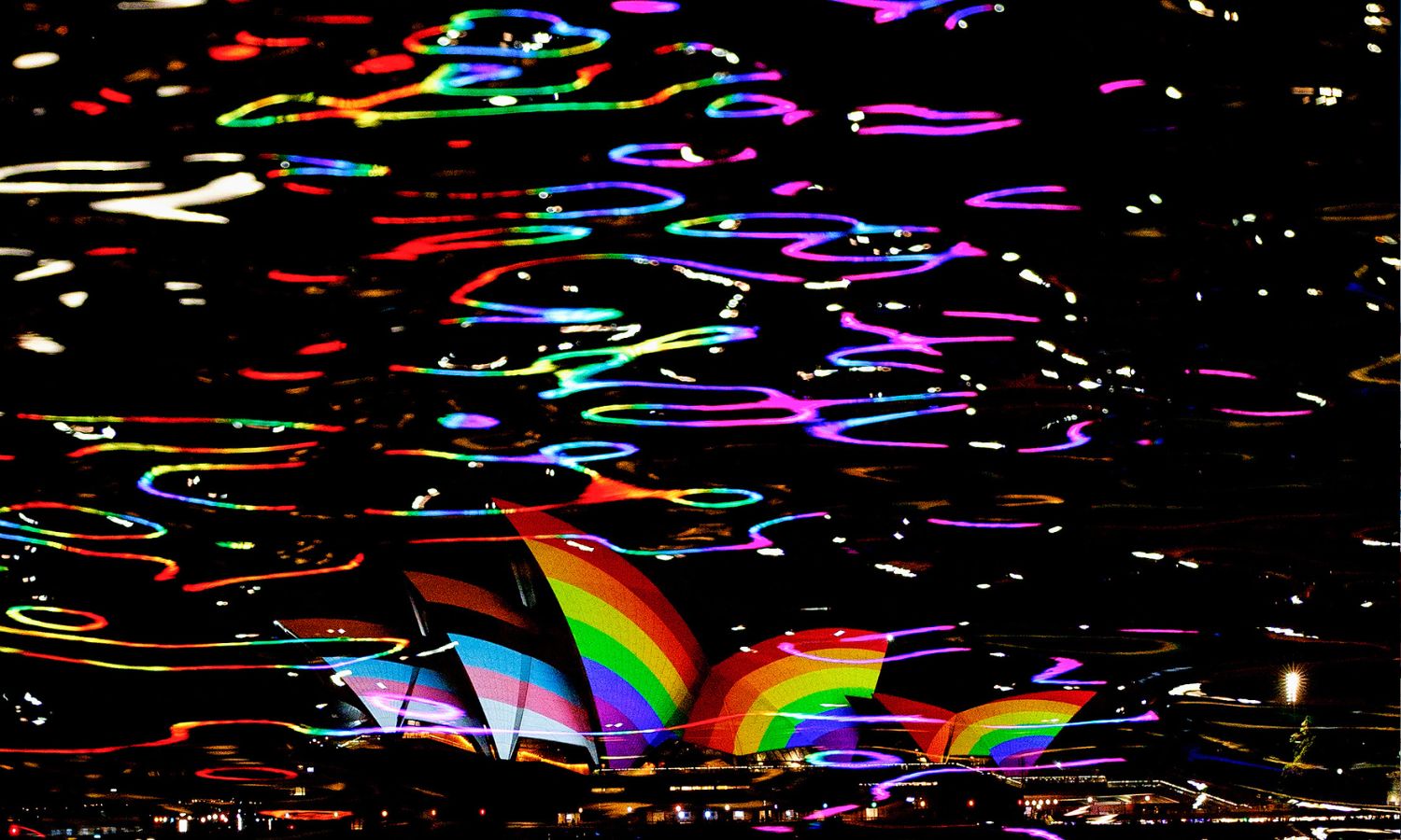 An image of the Opera House in Sydney lit up with the LGBTQIA+ pride flag to illustrate homophobia in Australia